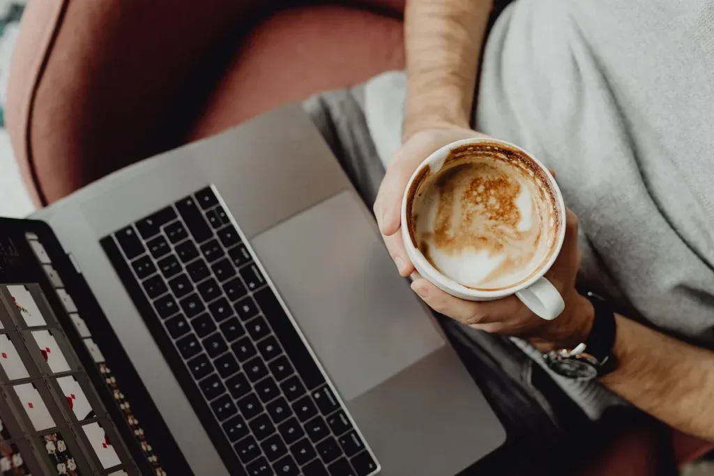 Praca zdalna z domu przy laptopie i kawie jako sposób na pogodzenie pracy z opieką nad rodzicem