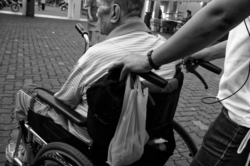 Opiekun pcha wózek inwalidzki ze starszym mężczyzną; po wyjściu ze szpitala łączy się różne dni wolne